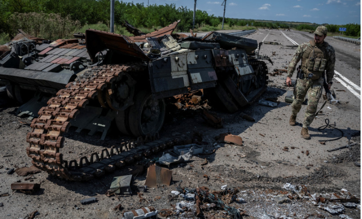 On August 25, 2023, a Ukrainian serviceman strolls past a wrecked Ukrainian tank in the town of Robotyne in the Zaporizhia area of Ukraine. [Reuters/Viacheslav Ratynsky]